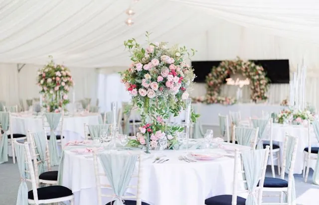 Marquee wedding breakfast with pink florals and sage drapes